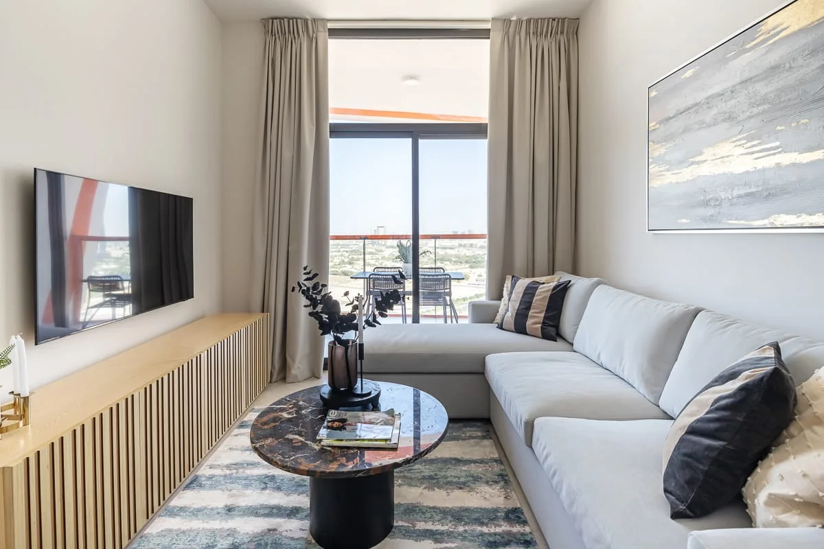A bright living room with a sectional sofa, coffee table, and large window.