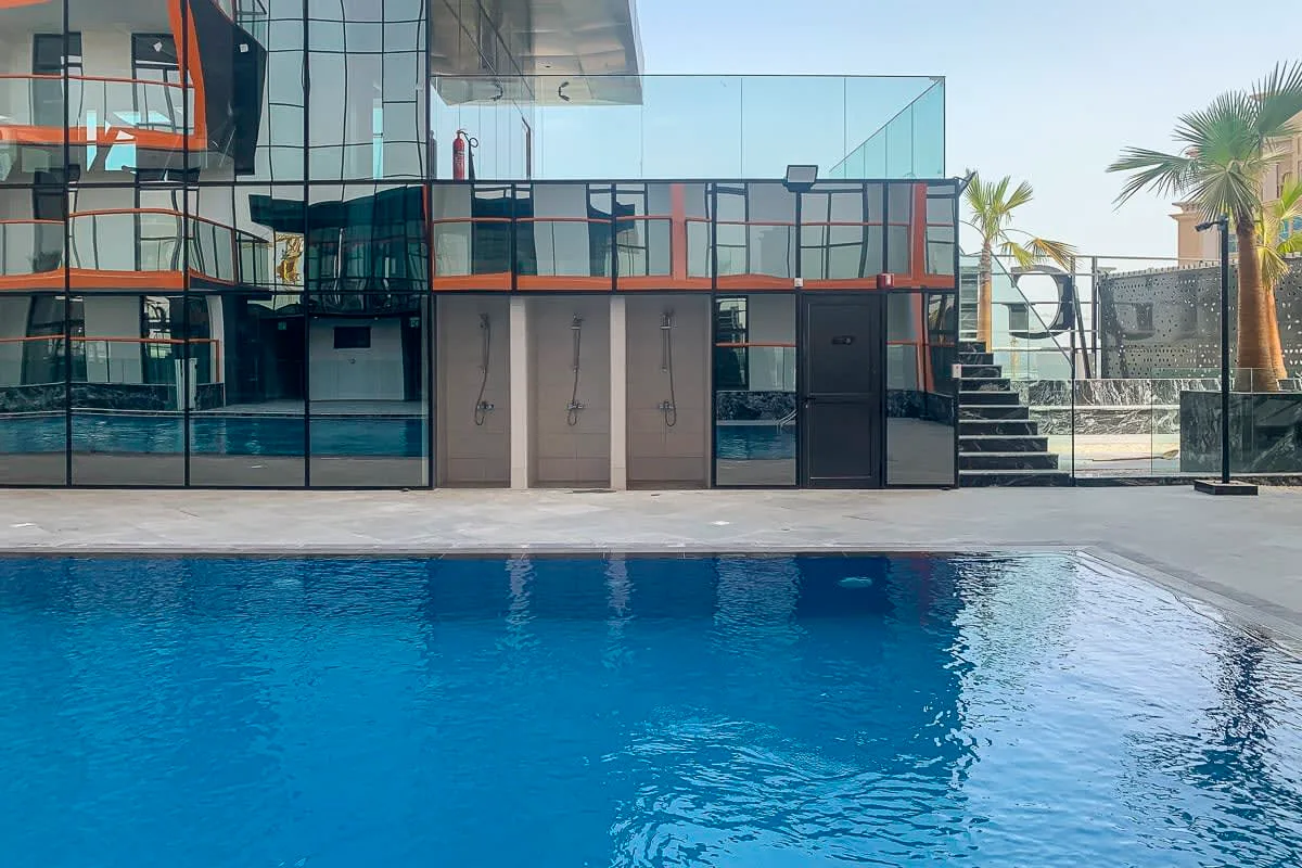 A swimming pool sits in front of a modern glass-fronted building.