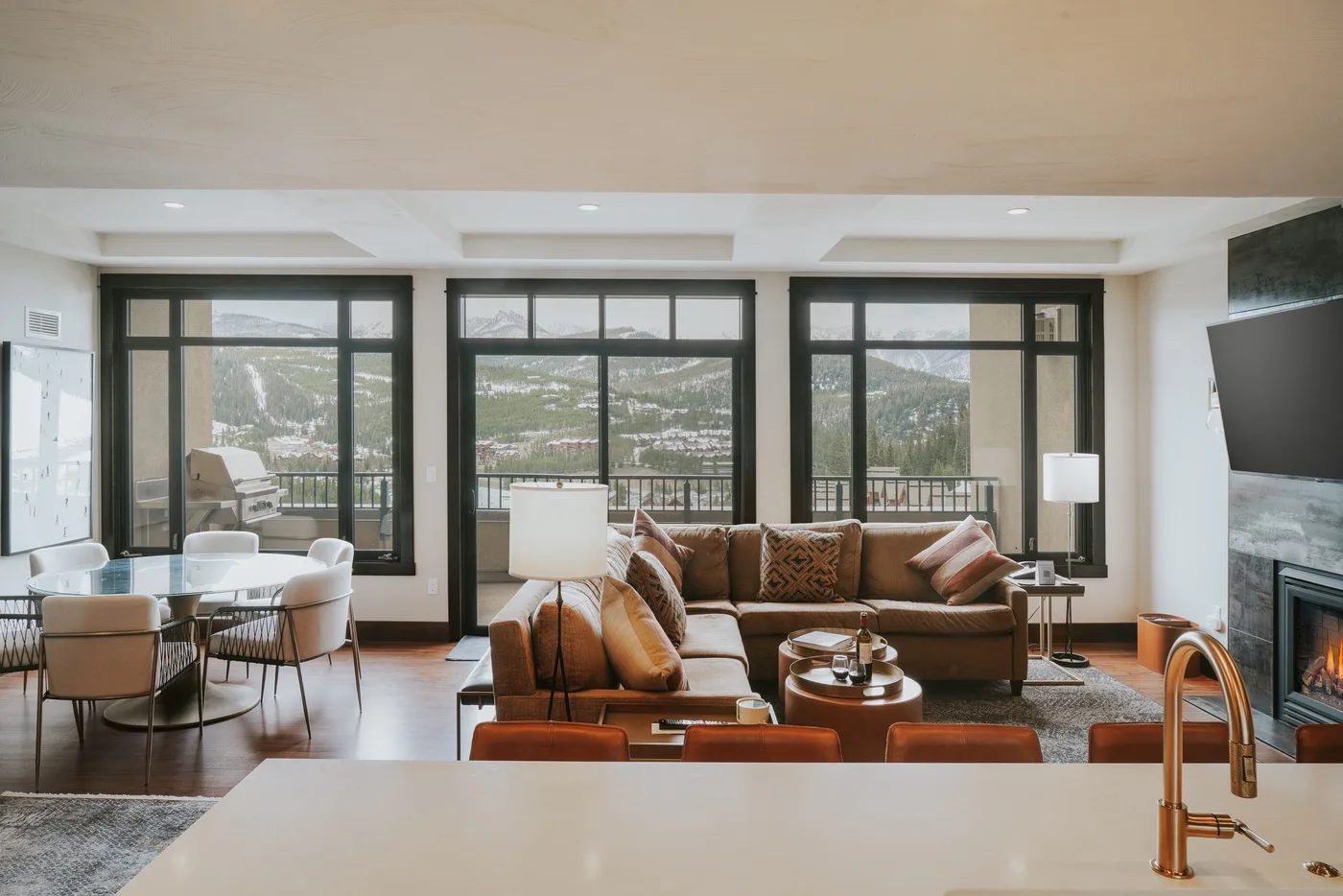 A living room with seating arranged in front of large windows overlooking a mountain valley.