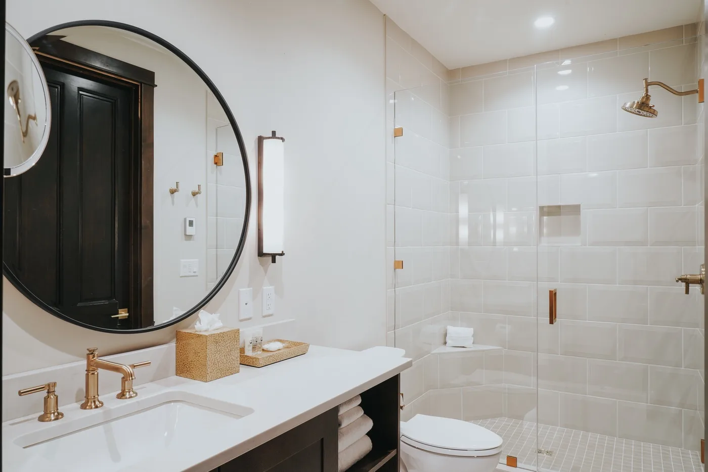 A bright bathroom with a white vanity and glass shower.
