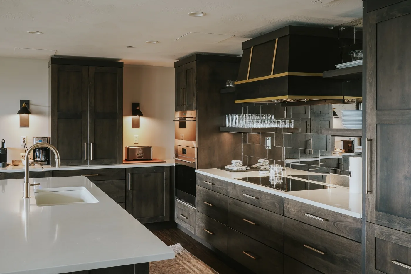A modern kitchen with dark cabinets, light countertops, and a large island.