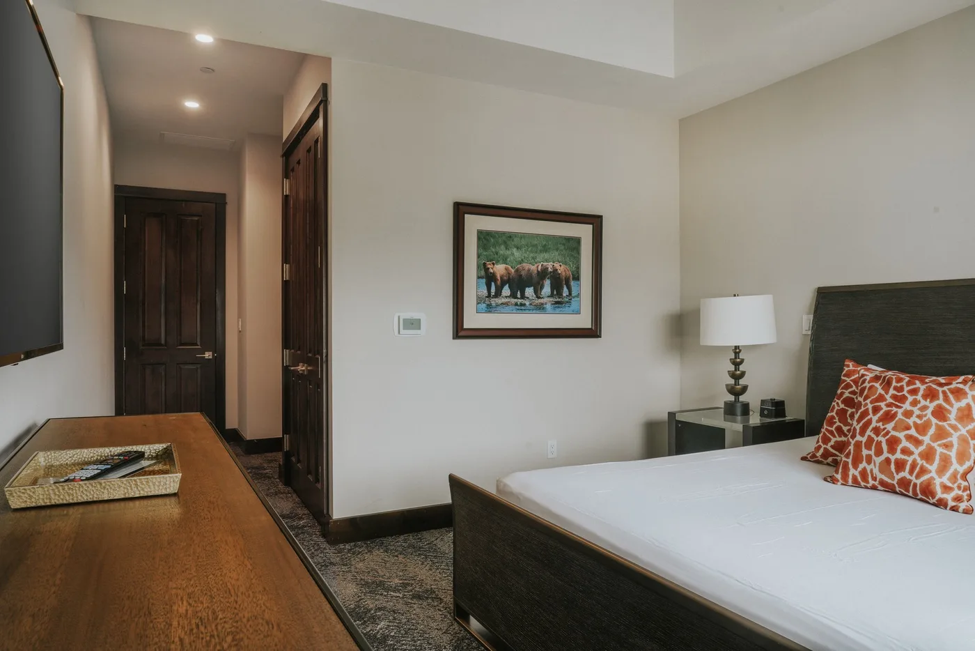 A bedroom with a neatly made bed and framed artwork on the wall.