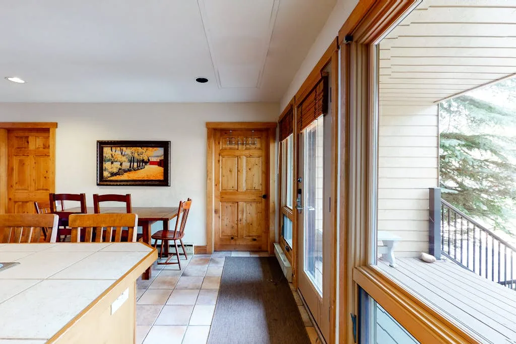 A dining area with wooden doors and windows opening onto a deck.
