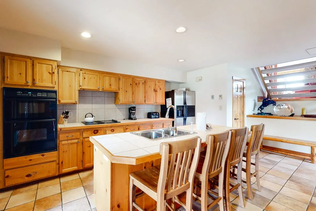 A kitchen with wooden cabinetry, a cooking island, and bar seating.
