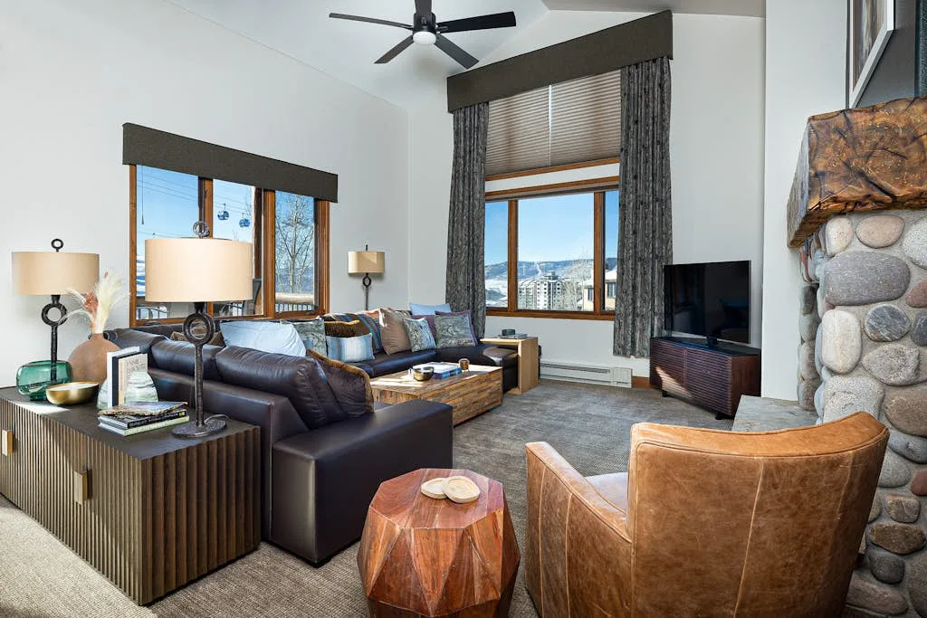 A living room with seating arranged around a low table and a television.