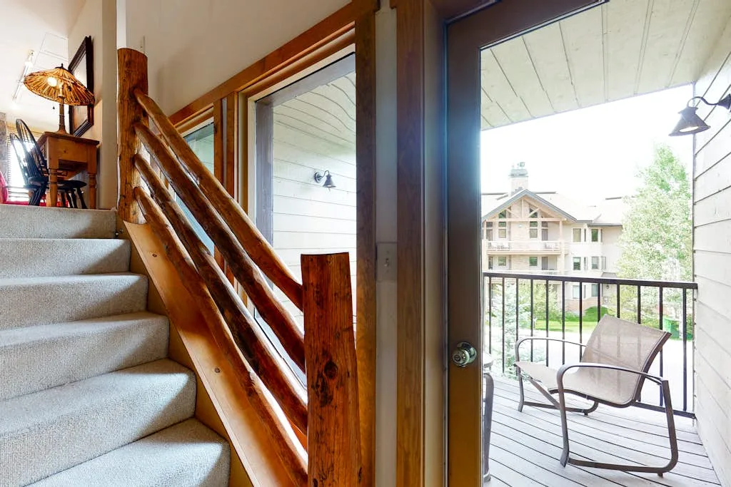A carpeted staircase opens onto a balcony with outdoor seating.