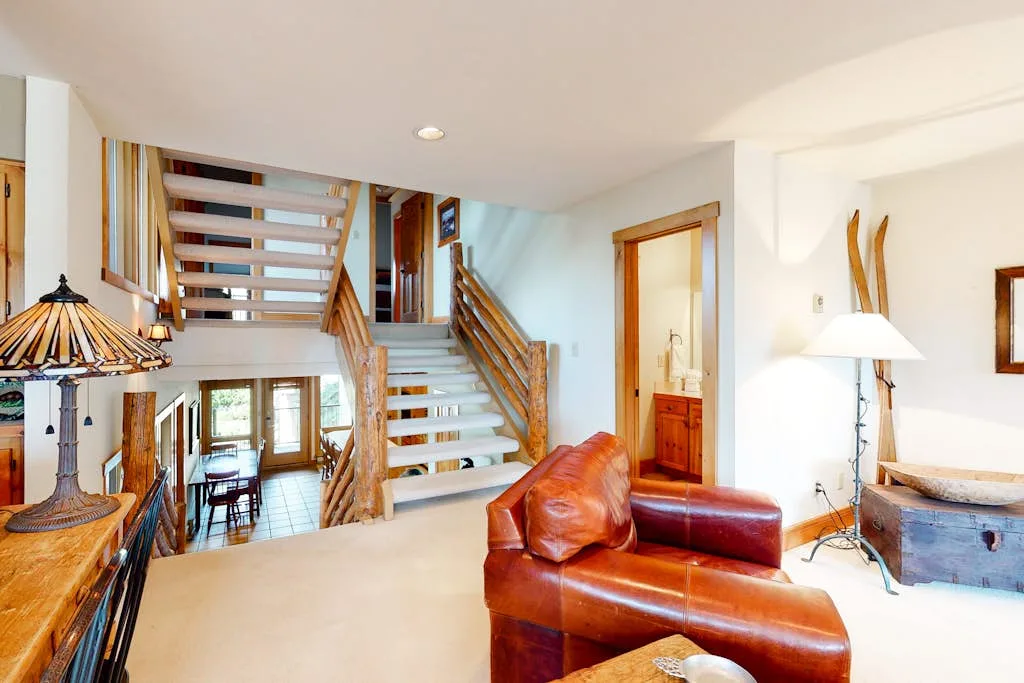 A bright living area with a leather seating arrangement beside a wooden staircase.