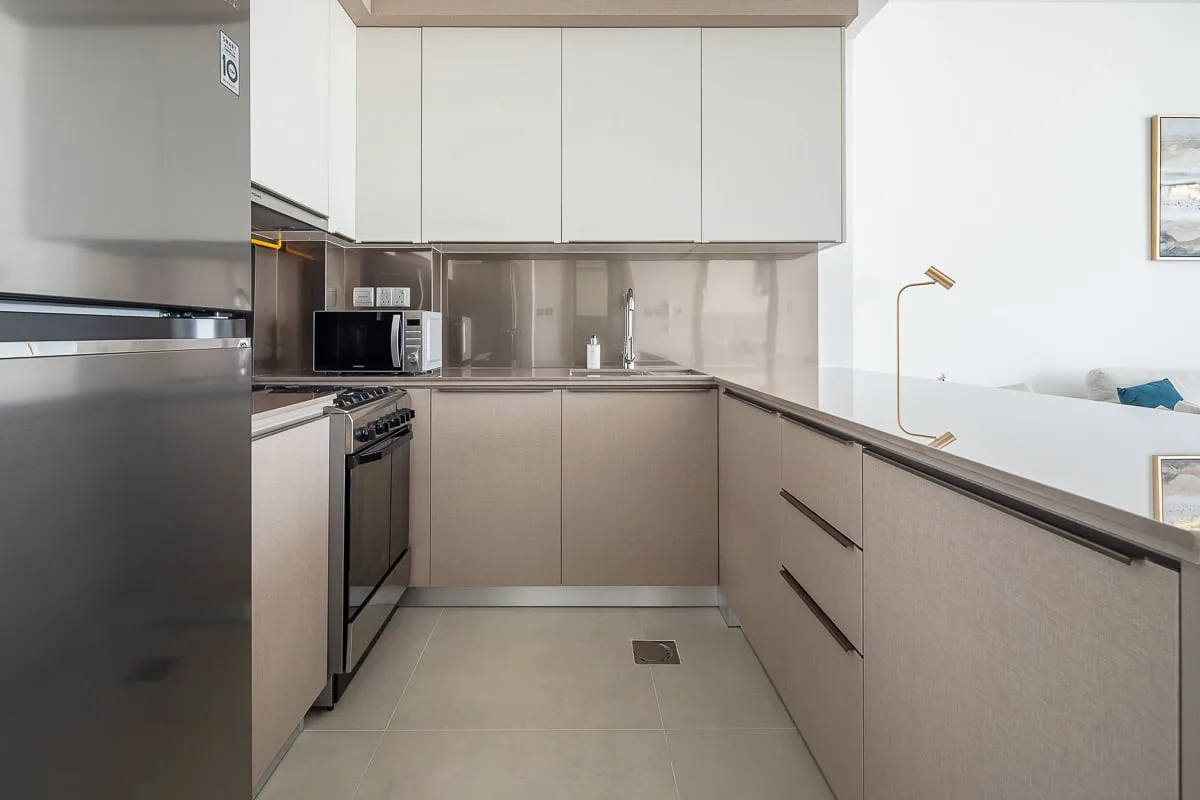 A modern kitchen with light cabinets, dark countertops, and stainless steel appliances.