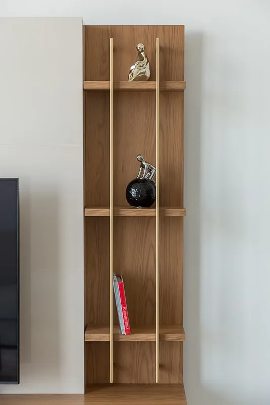 A wooden display shelf with small decorative sculptures and books.