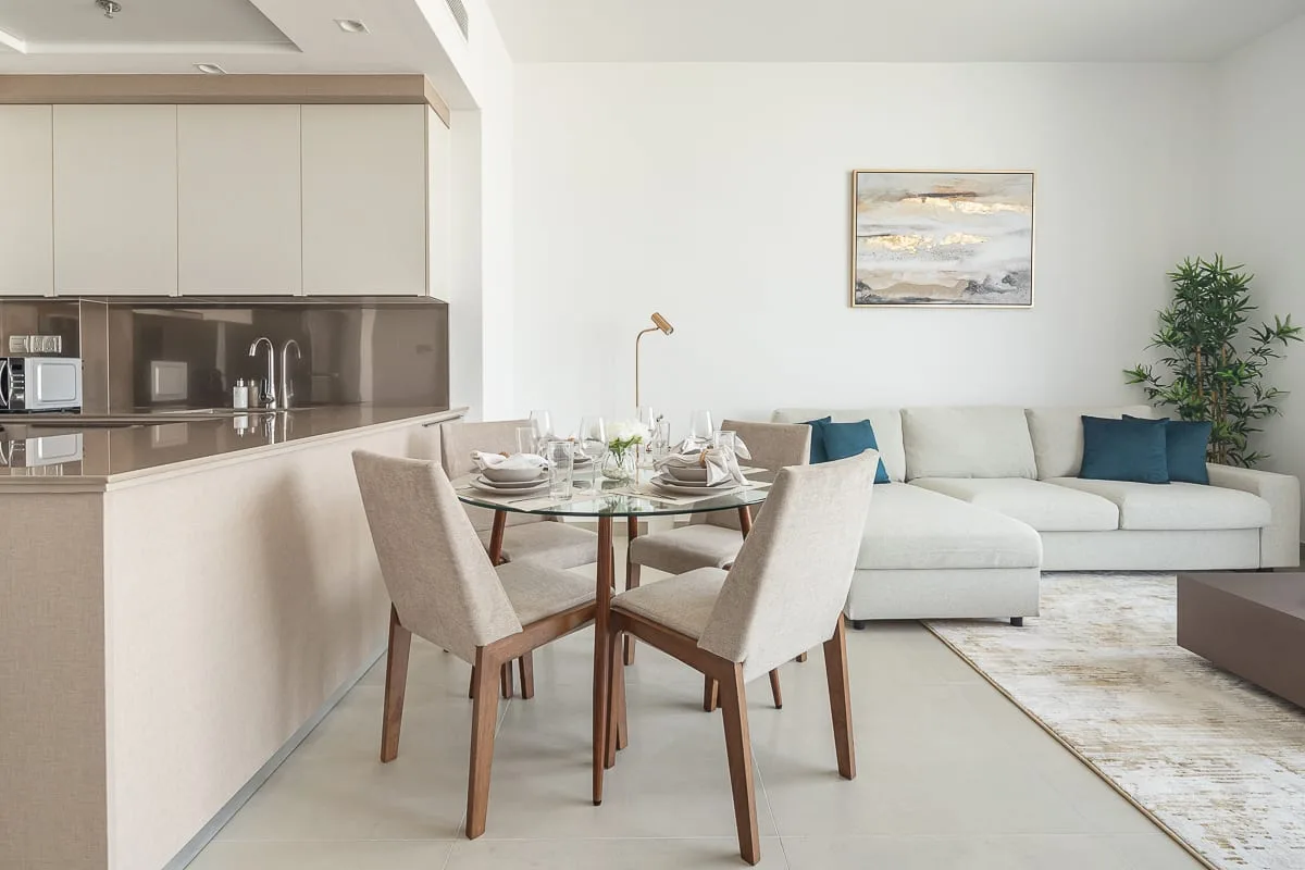 A bright open-plan living and dining area with a round table beside the seating.