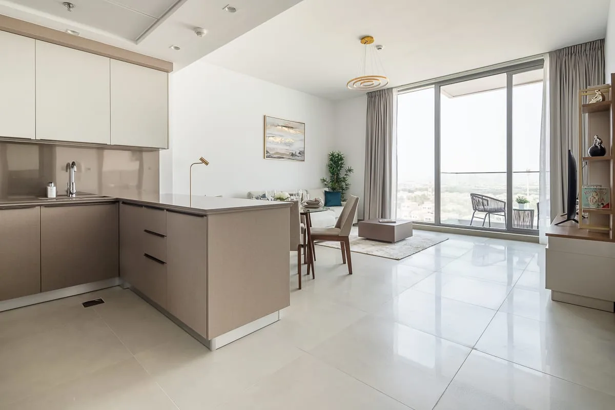 A bright open-plan kitchen and living area with large windows and dining seating.
