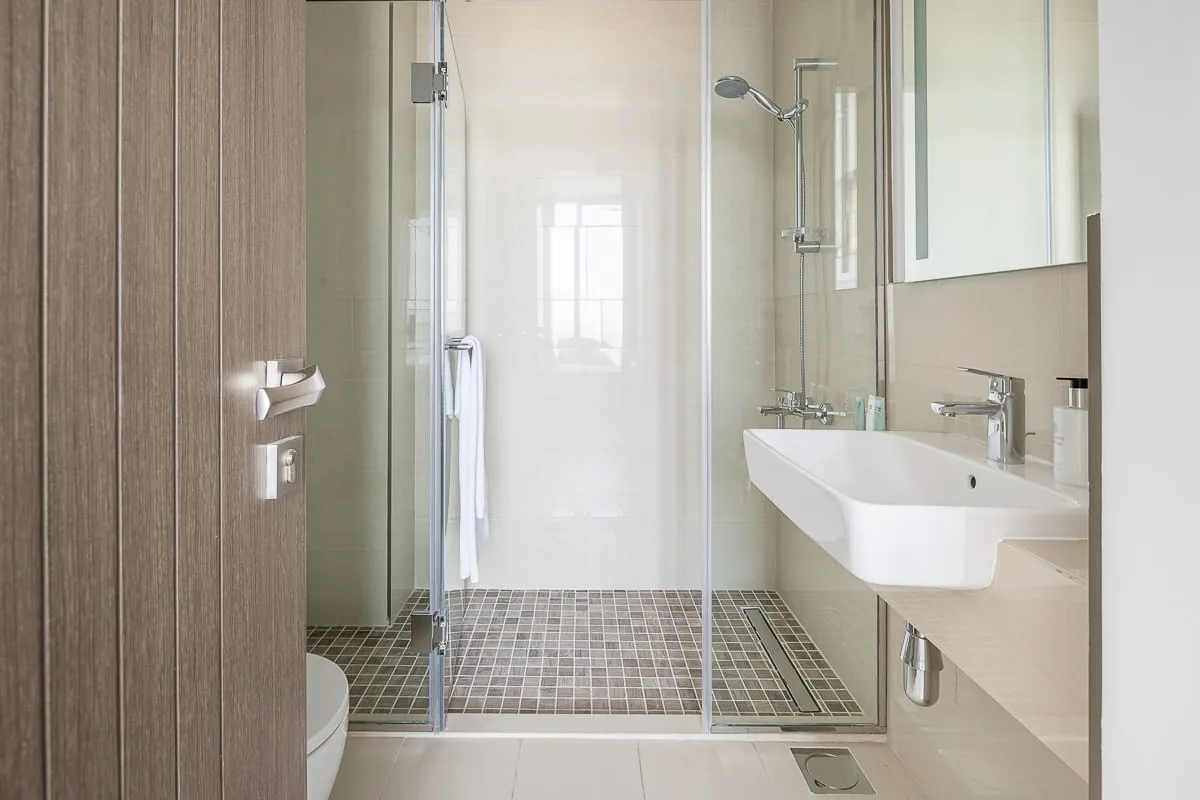 A bright bathroom with a glass shower and a wall-mounted sink.