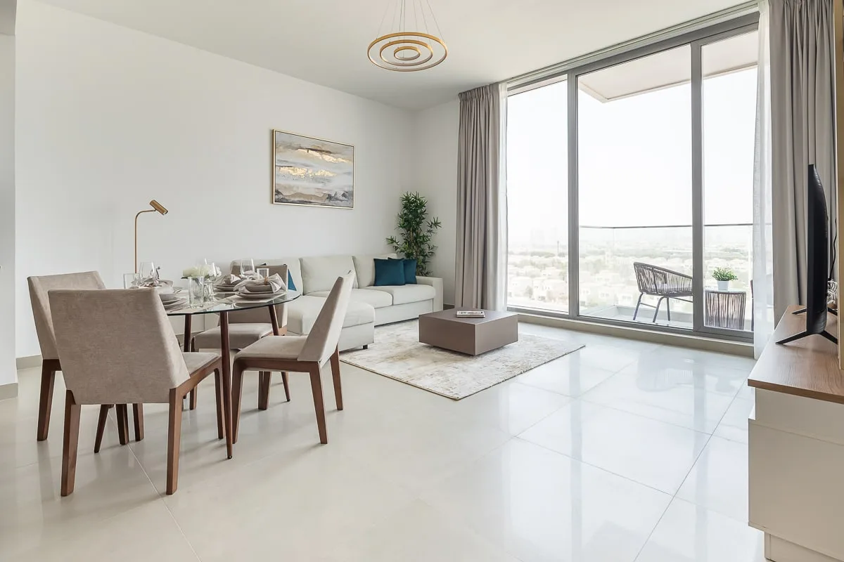 A bright living and dining area opens onto a balcony through large windows.