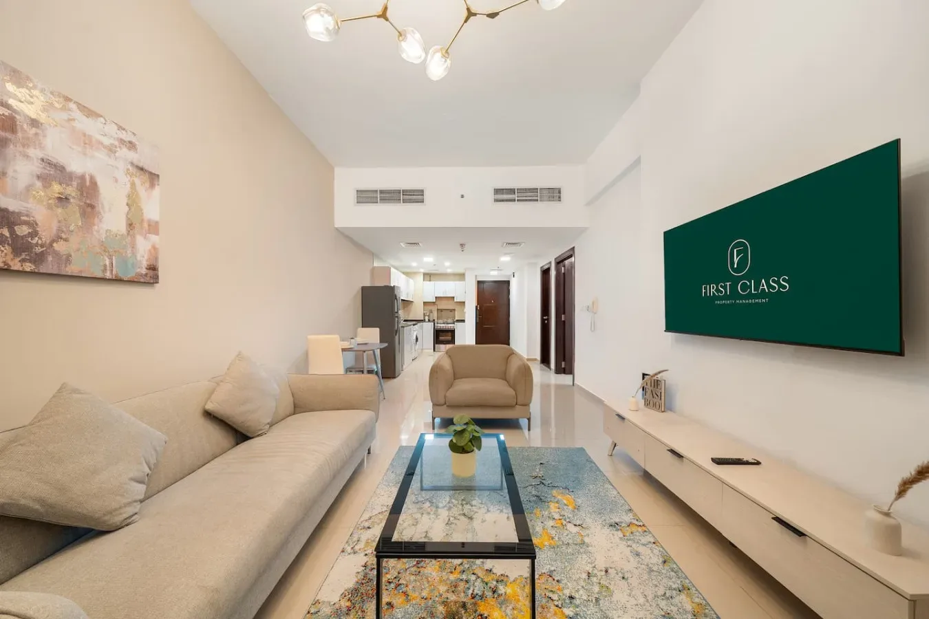 A living room with seating, a glass coffee table, and a wall-mounted television.