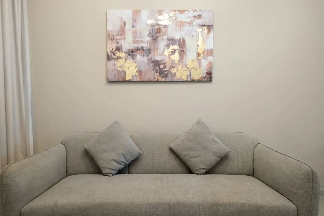 A living room with a gray sofa and abstract artwork on the wall.