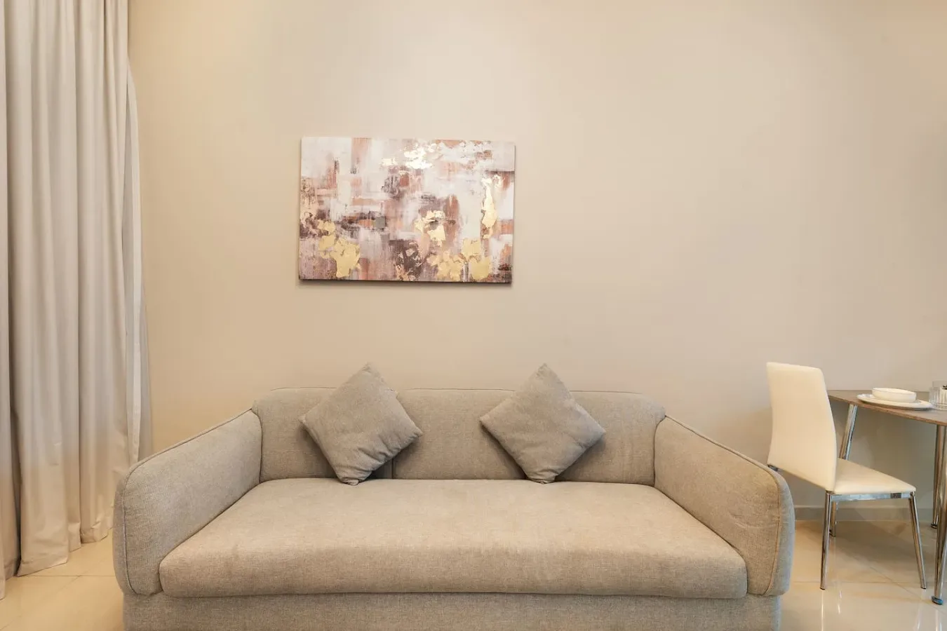 A living room with a beige sofa and abstract artwork on the wall.