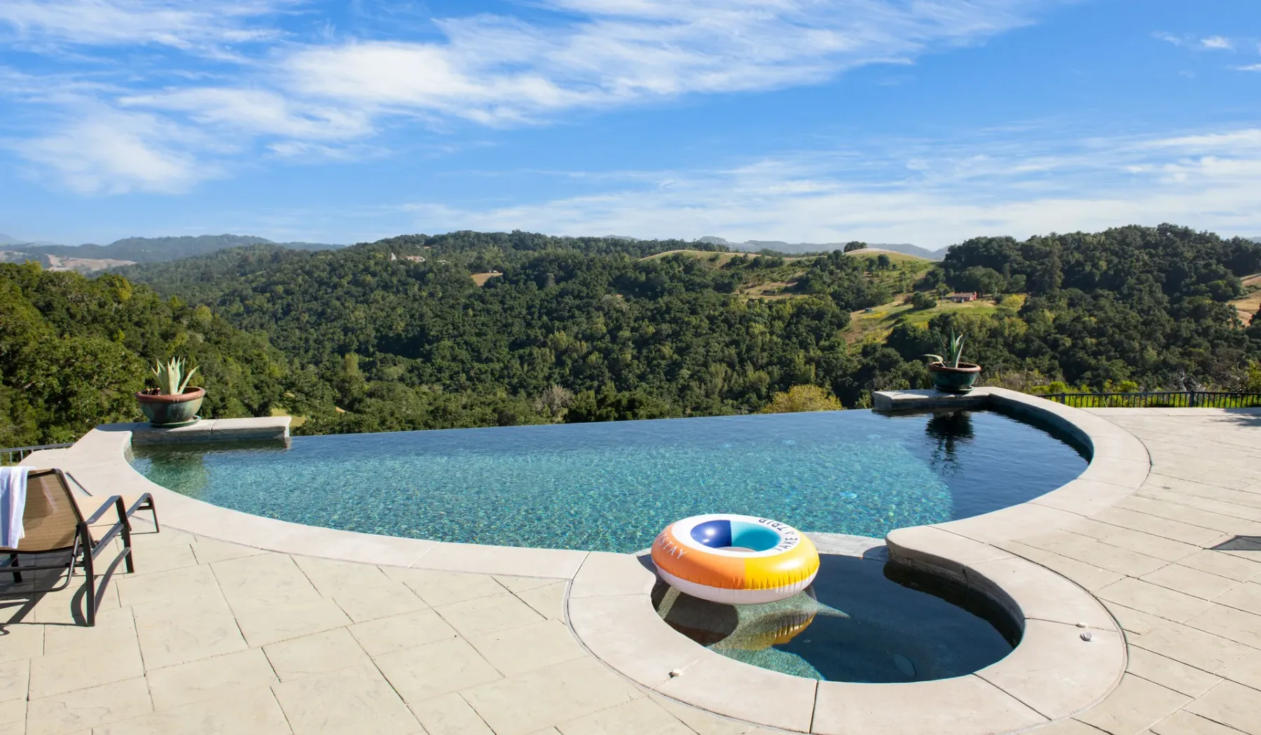 Una piscina al aire libre ofrece vistas a colinas verdes bajo un cielo parcialmente nublado.