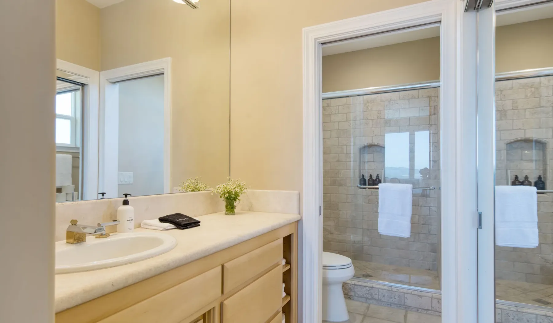 Un tocador de baño con lavabo frente a una zona de ducha con azulejos.
