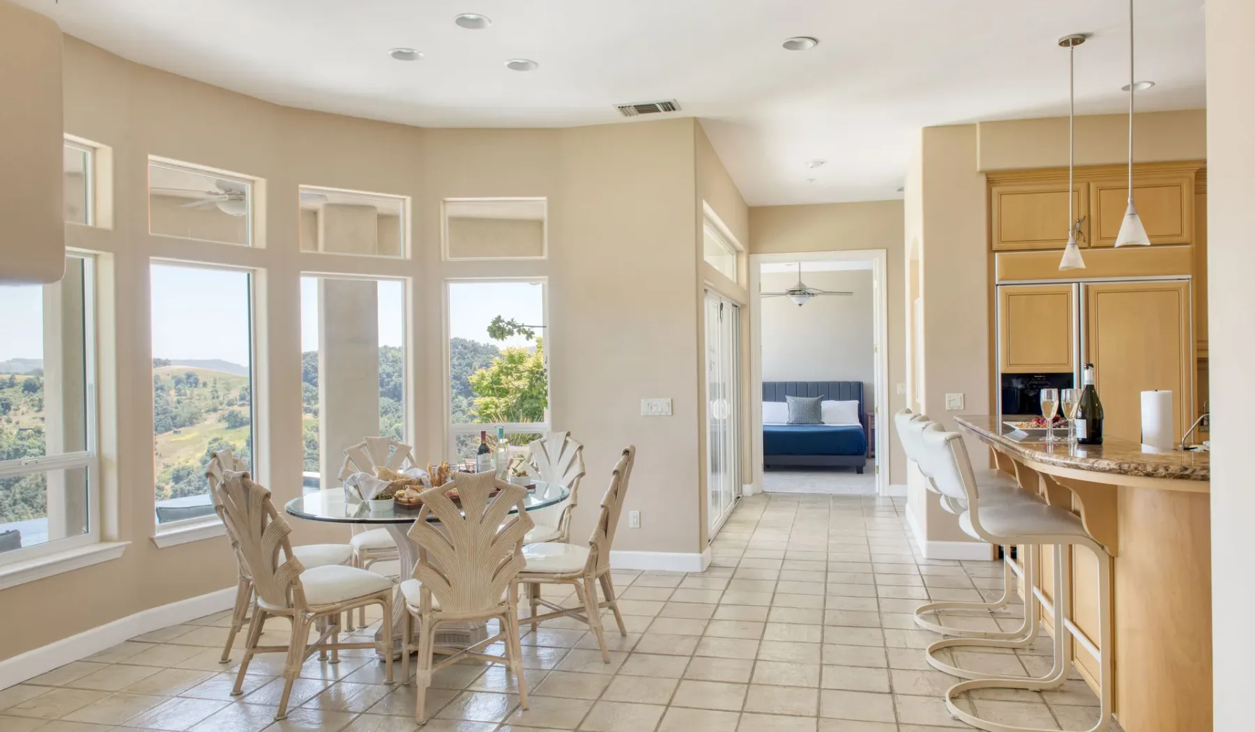 Un comedor luminoso con una mesa junto a una barra de cocina y ventanas grandes.