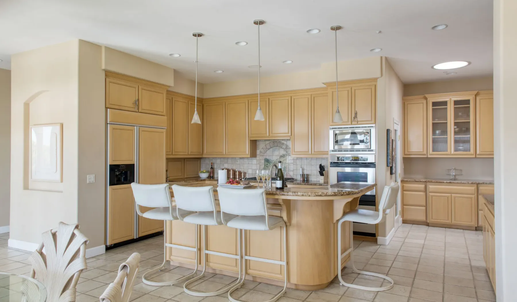 Una cocina luminosa con gabinetes de madera, una isla y asientos de barra.
