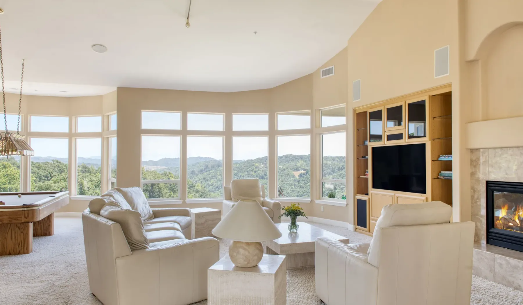 Una sala luminosa con asientos, grandes ventanas y una chimenea.