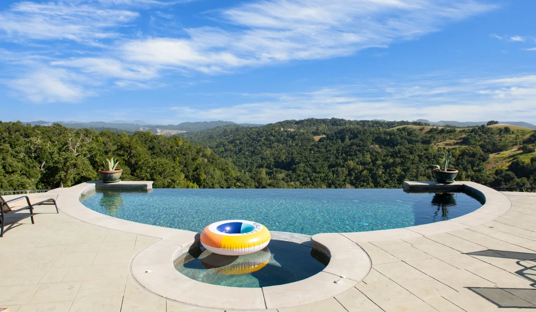 Una piscina con una sección circular poco profunda ofrece vistas a colinas verdes.