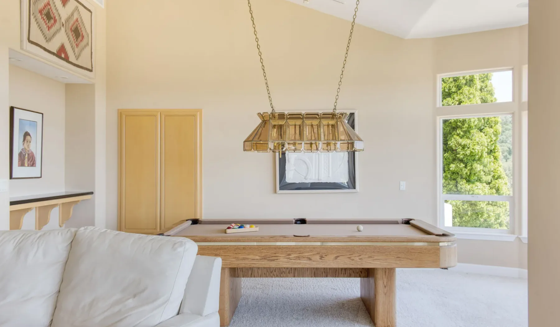Una luminosa sala de juegos cuenta con una mesa de billar junto a una ventana grande.