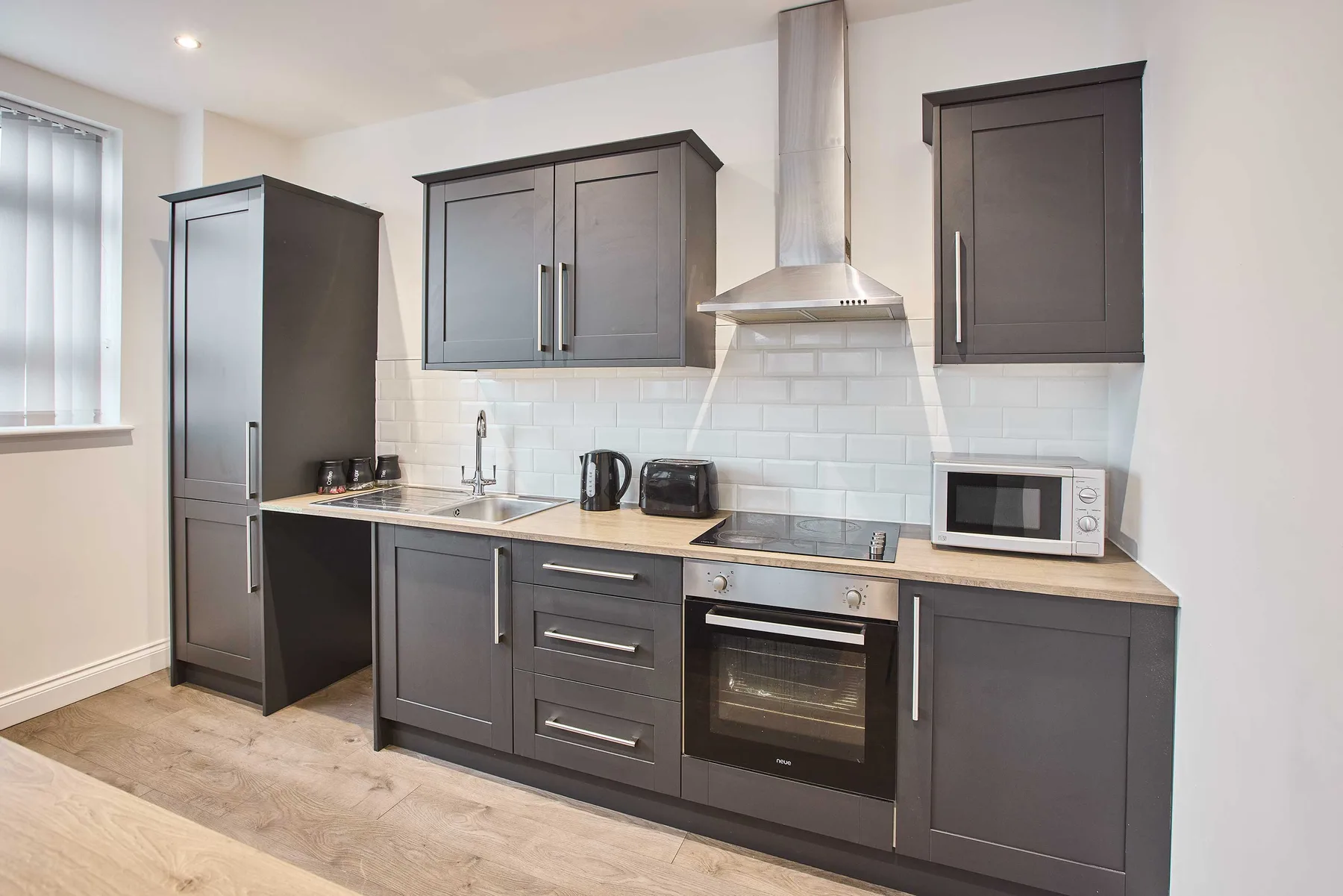 Una cocina moderna con gabinetes oscuros, una encimera y electrodomésticos integrados.