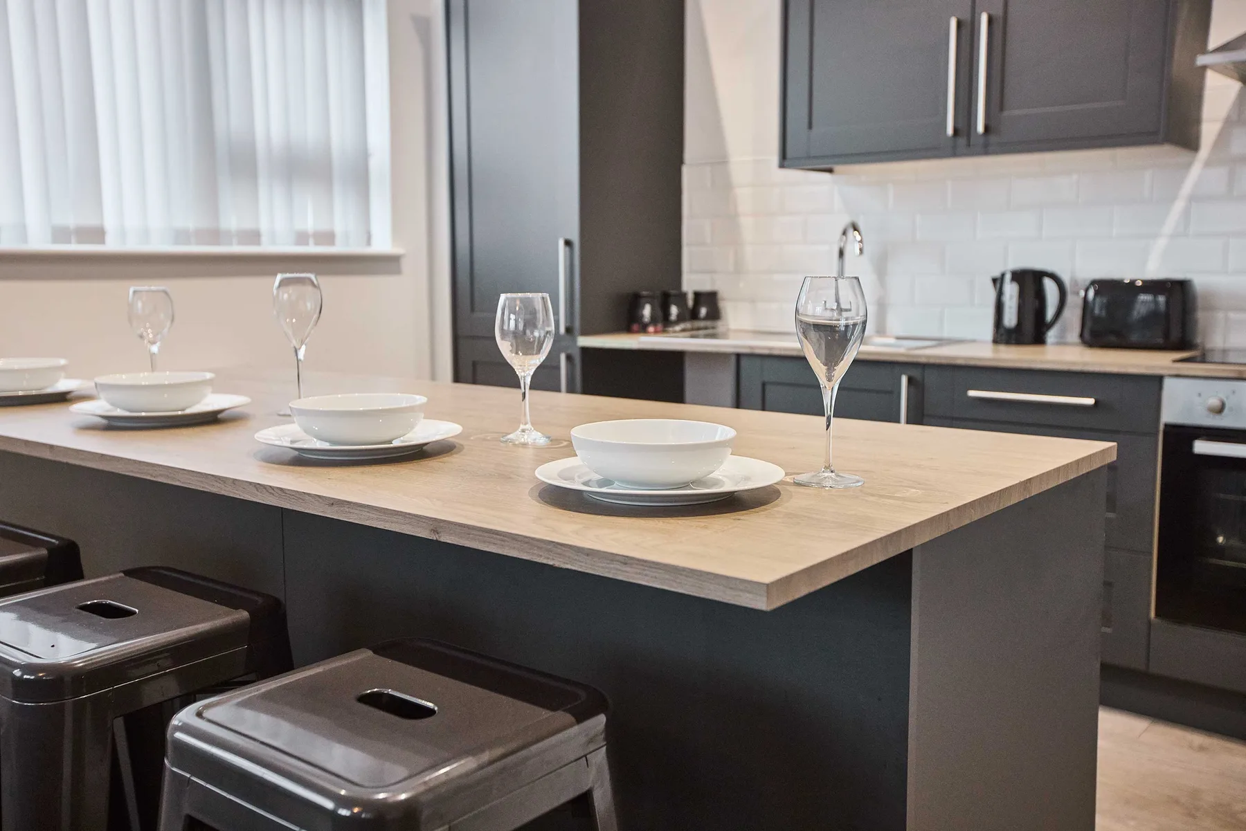 Una cocina moderna con una isla de comedor preparada con platos y copas.