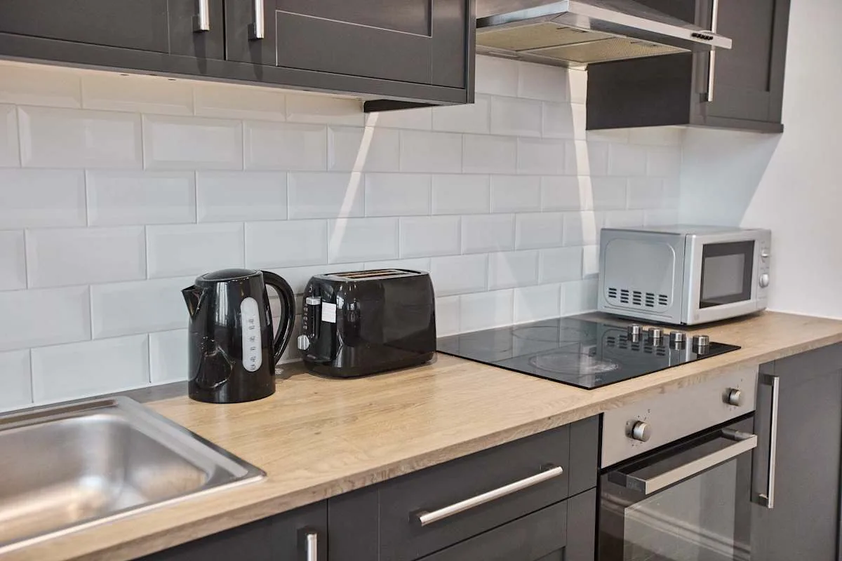 Una cocina moderna con armarios oscuros, una encimera y pequeños electrodomésticos.
