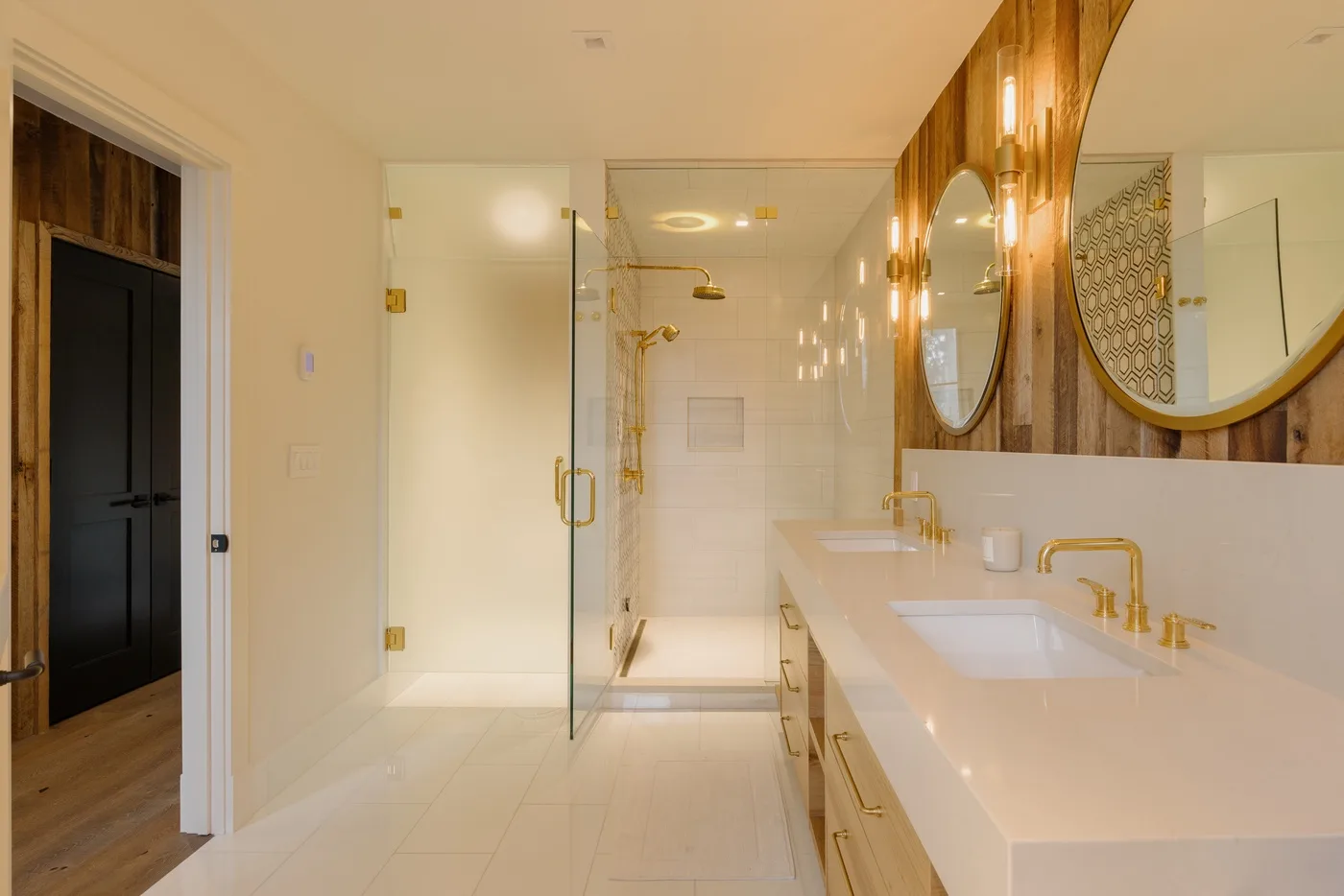 Un baño luminoso con una ducha de vidrio y un mueble de lavabo largo.