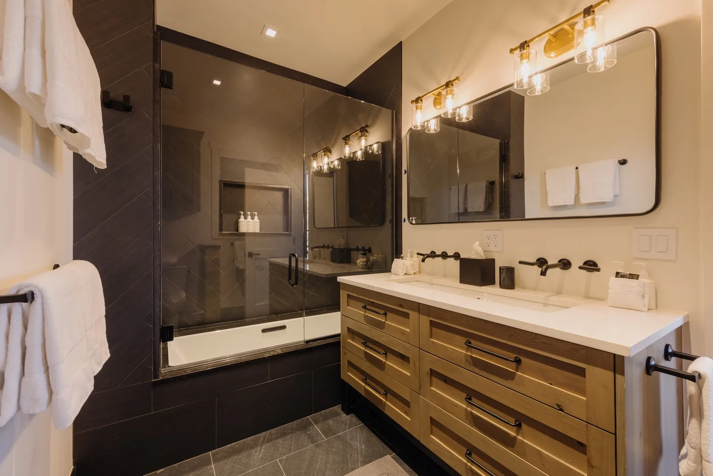 Un baño moderno con ducha de vidrio y un amplio tocador bajo un espejo.