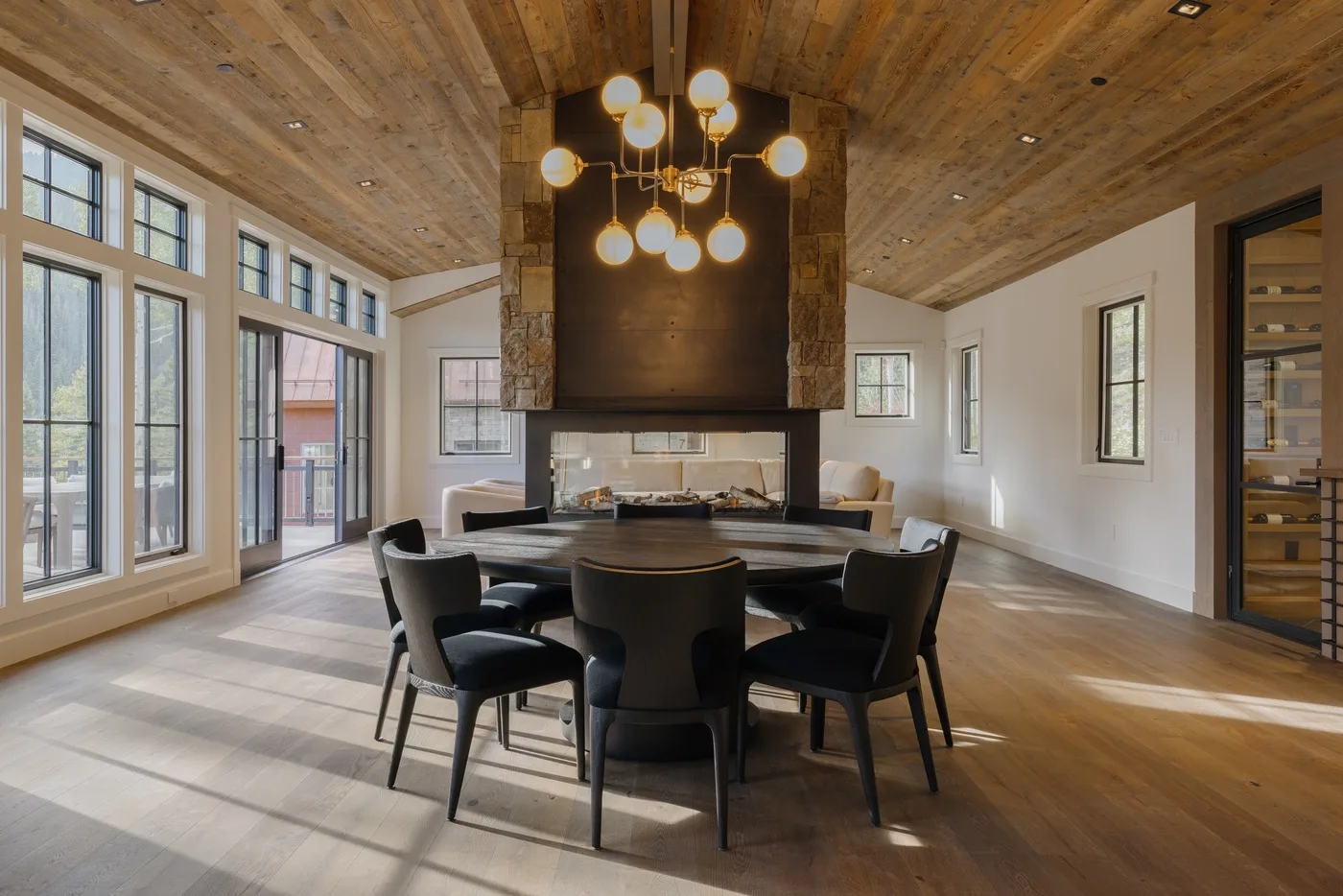 A dining area with a round table and chairs beneath a hanging light.