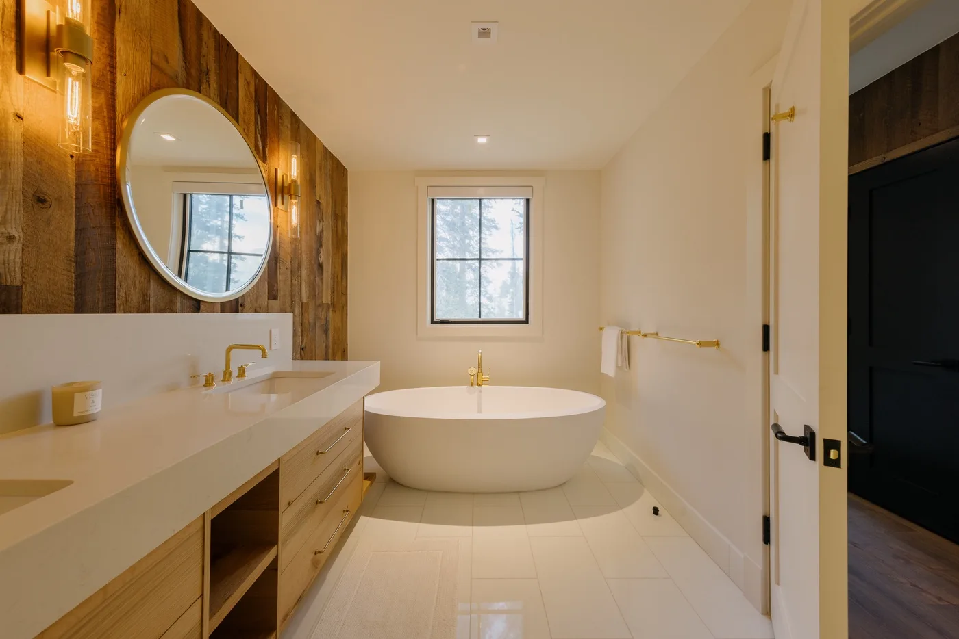 Un baño luminoso con una bañera exenta y un lavabo alargado.