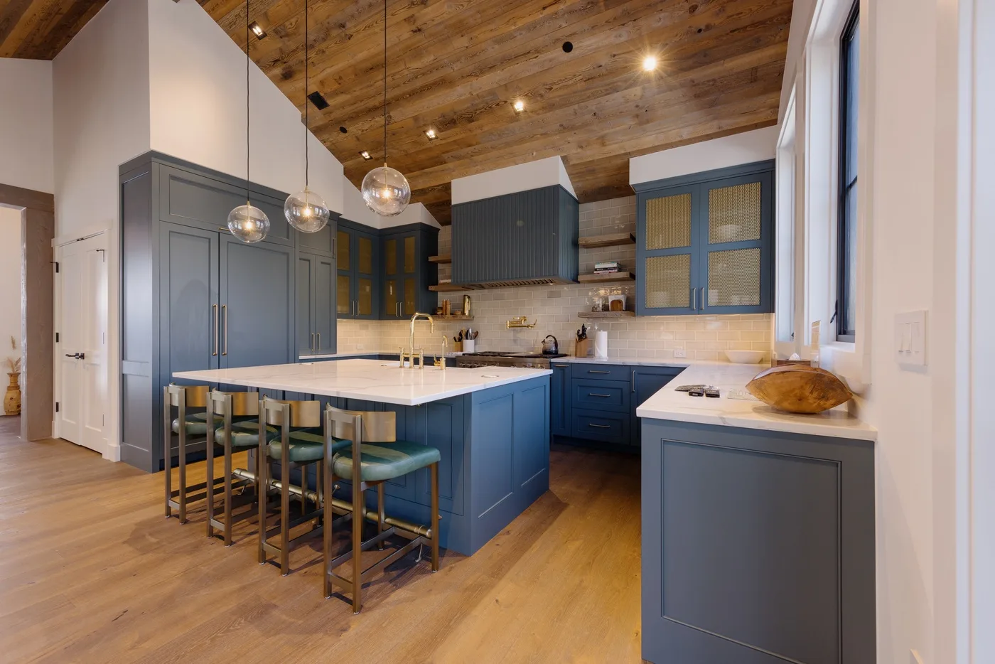 Una cocina amplia con gabinetes azules, una isla grande y lámparas colgantes.