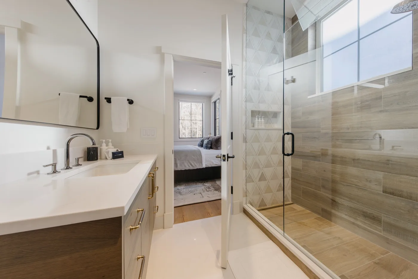 Un baño luminoso con un tocador largo y una ducha con mampara de vidrio.
