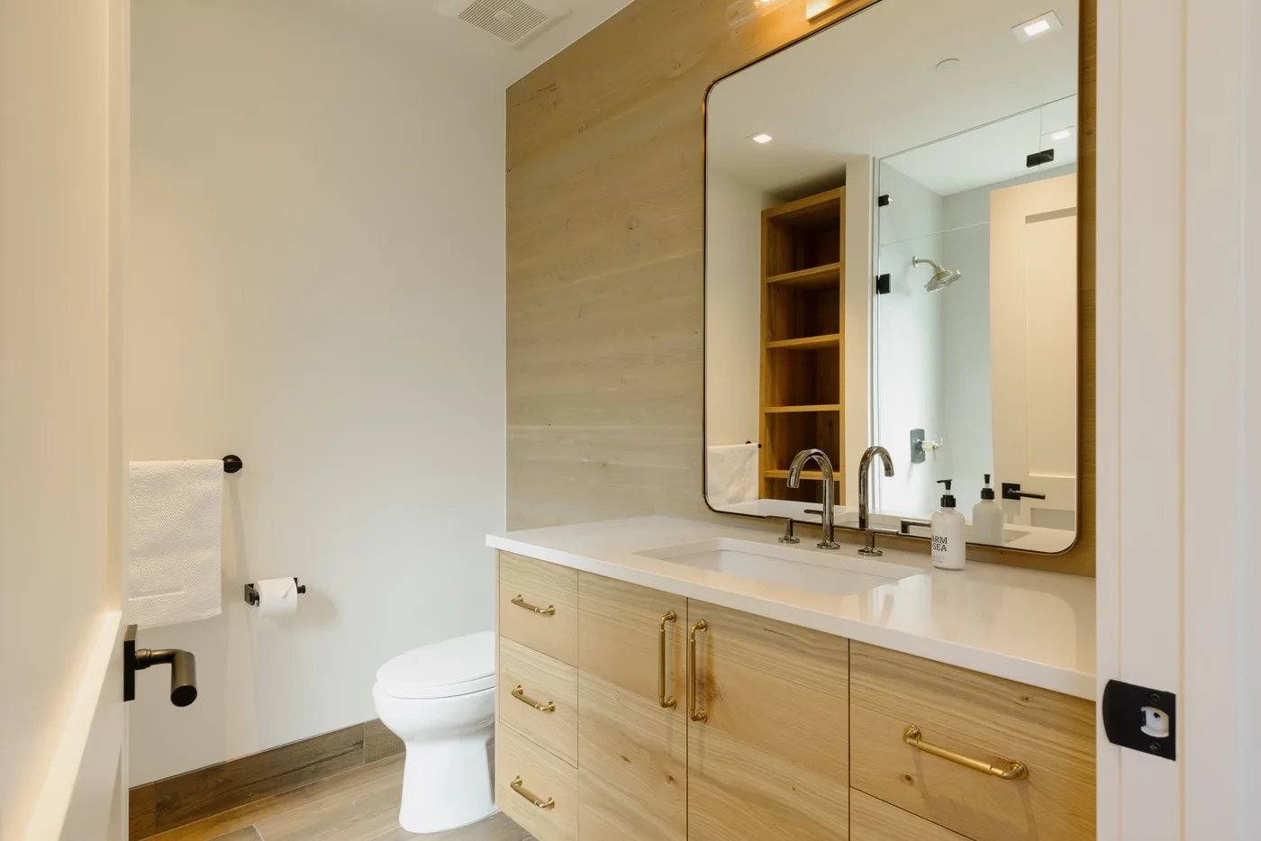 Lavabo de baño con un espejo amplio, junto a un inodoro.