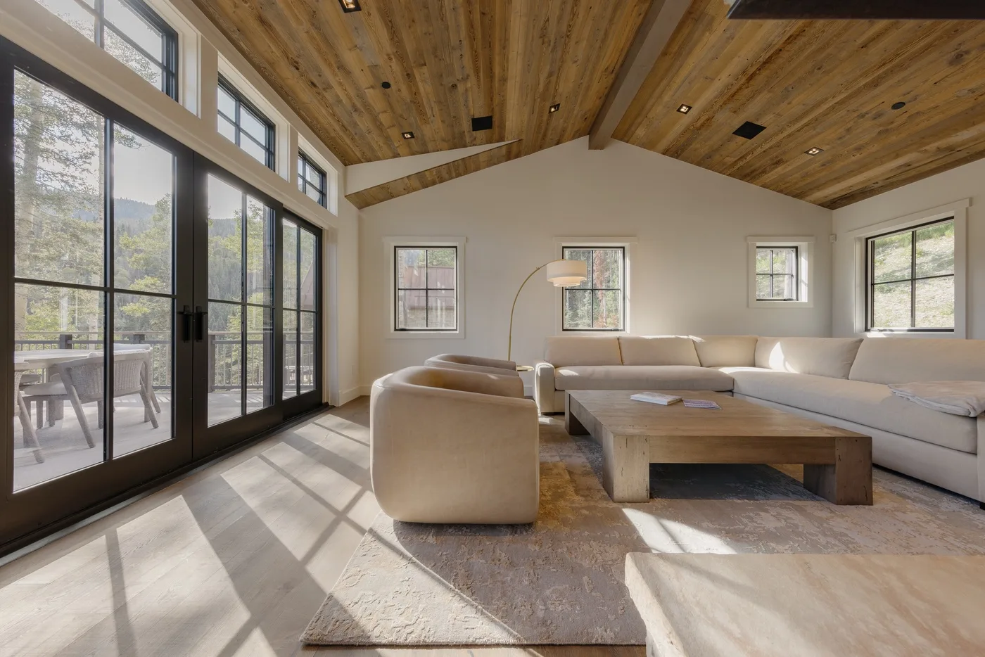 Una sala luminosa con amplias ventanas, asientos y una mesa de centro de madera.