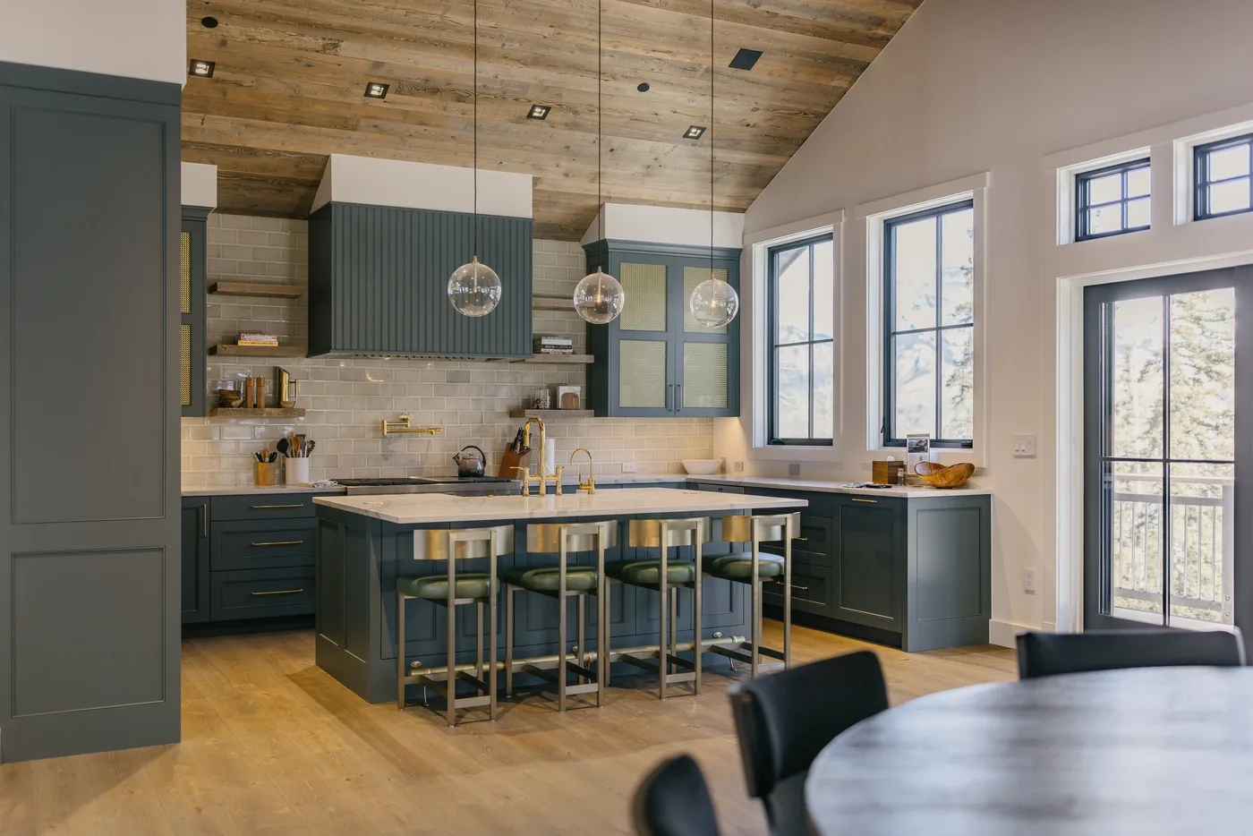 Una cocina amplia cuenta con una isla central, gabinetes oscuros y ventanas grandes.