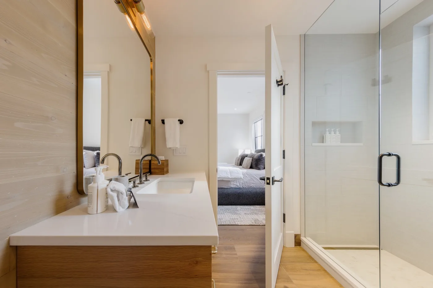 Un baño luminoso con un tocador largo junto a una ducha de vidrio.