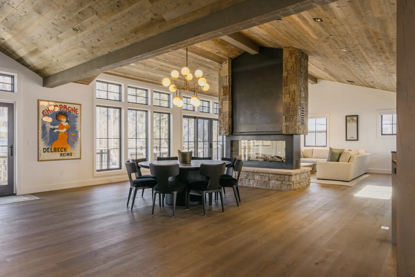 Un espacio abierto de sala y comedor con una chimenea de piedra central y una mesa.