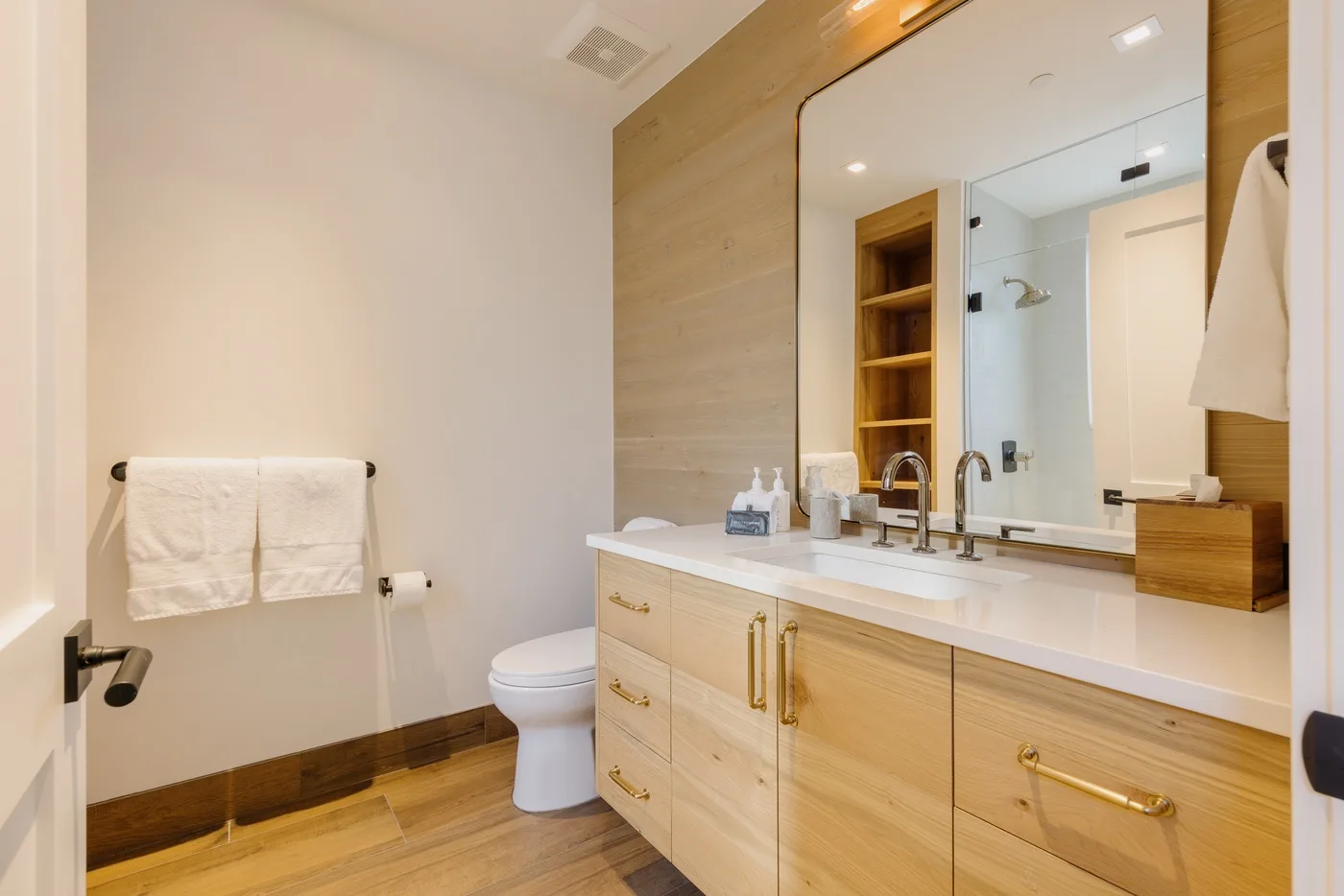Un baño con un tocador blanco, un espejo grande y un inodoro.