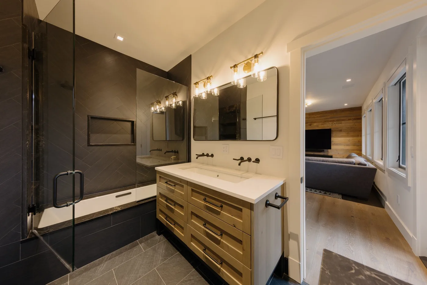Un baño con ducha de vidrio, bañera y tocador junto a un dormitorio.