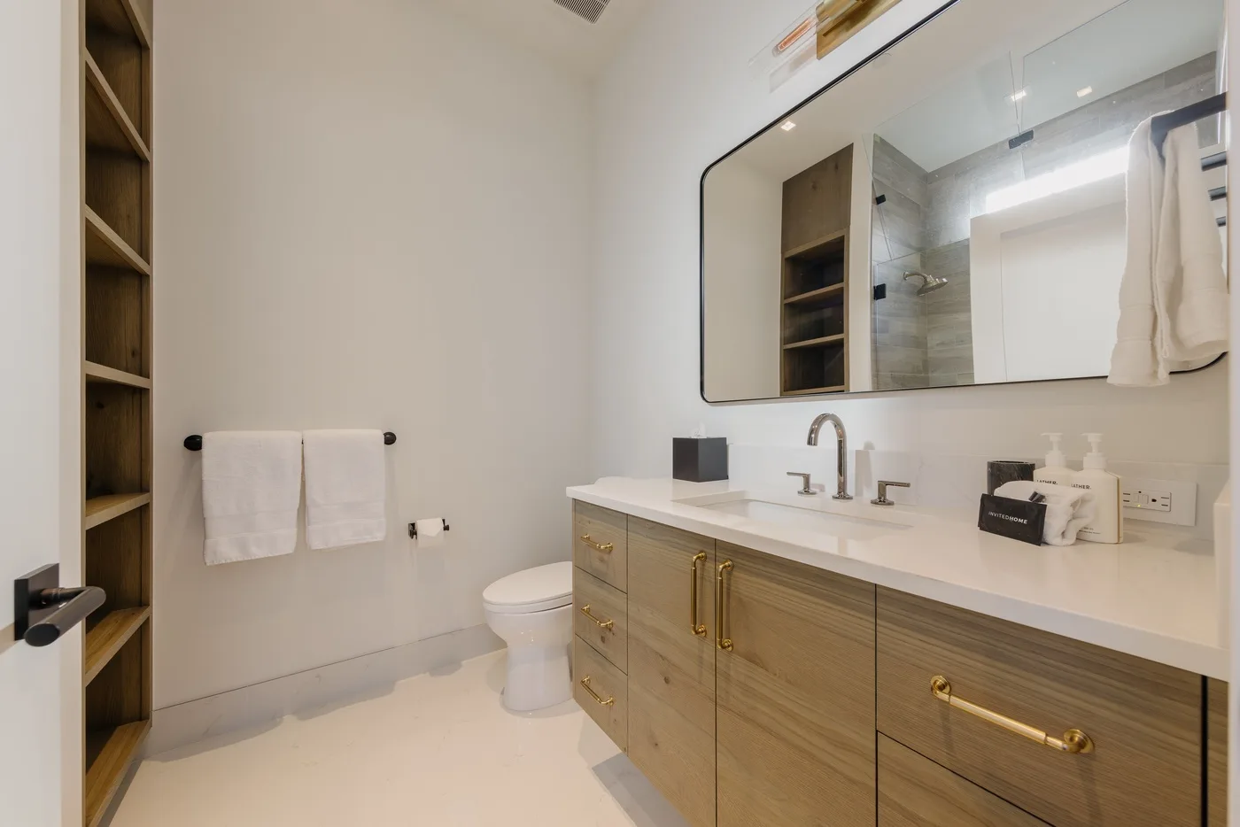 Un baño luminoso con un tocador largo, lavabo y espejo de pared.