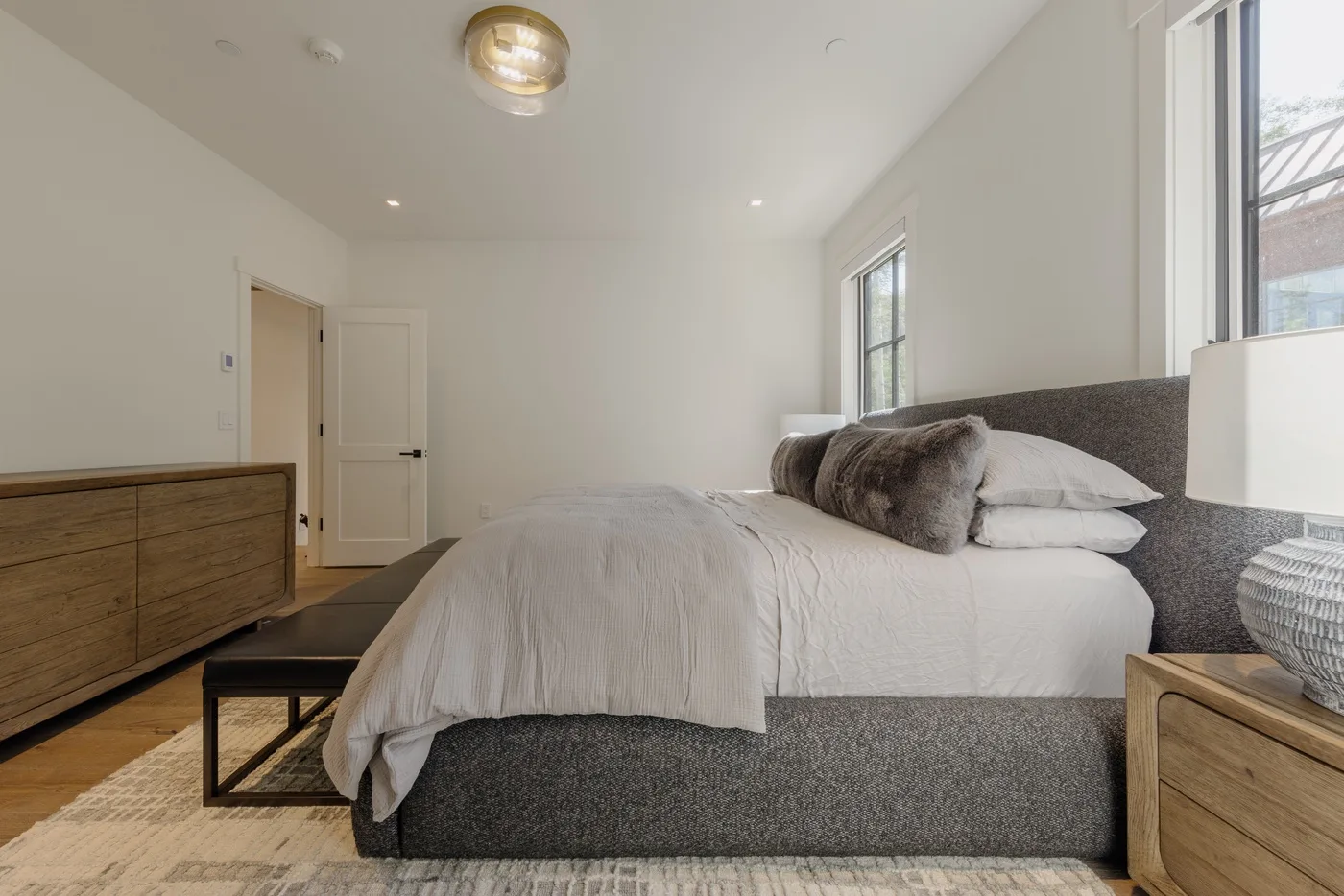 Un dormitorio luminoso con una cama tendida y muebles de madera.