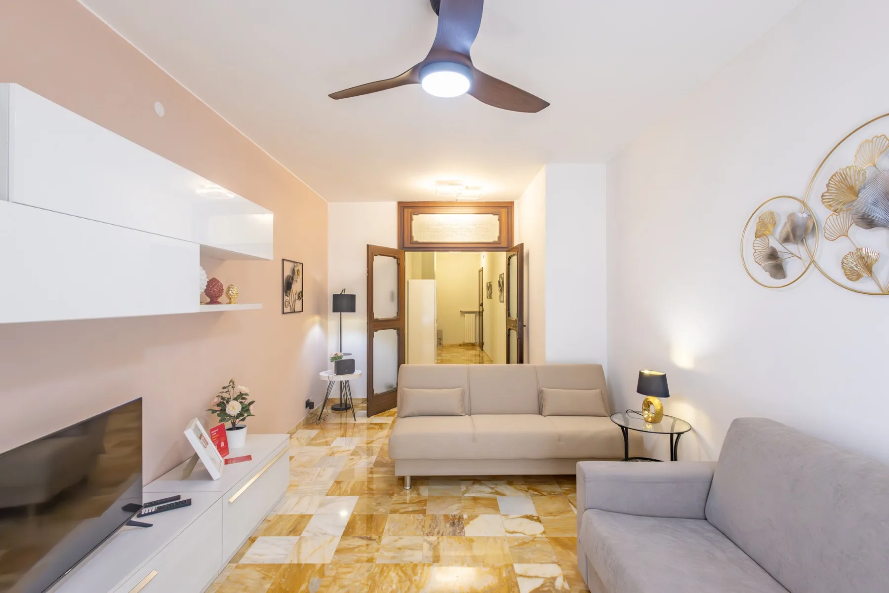 A living room with seating, a television, and a doorway to another room.