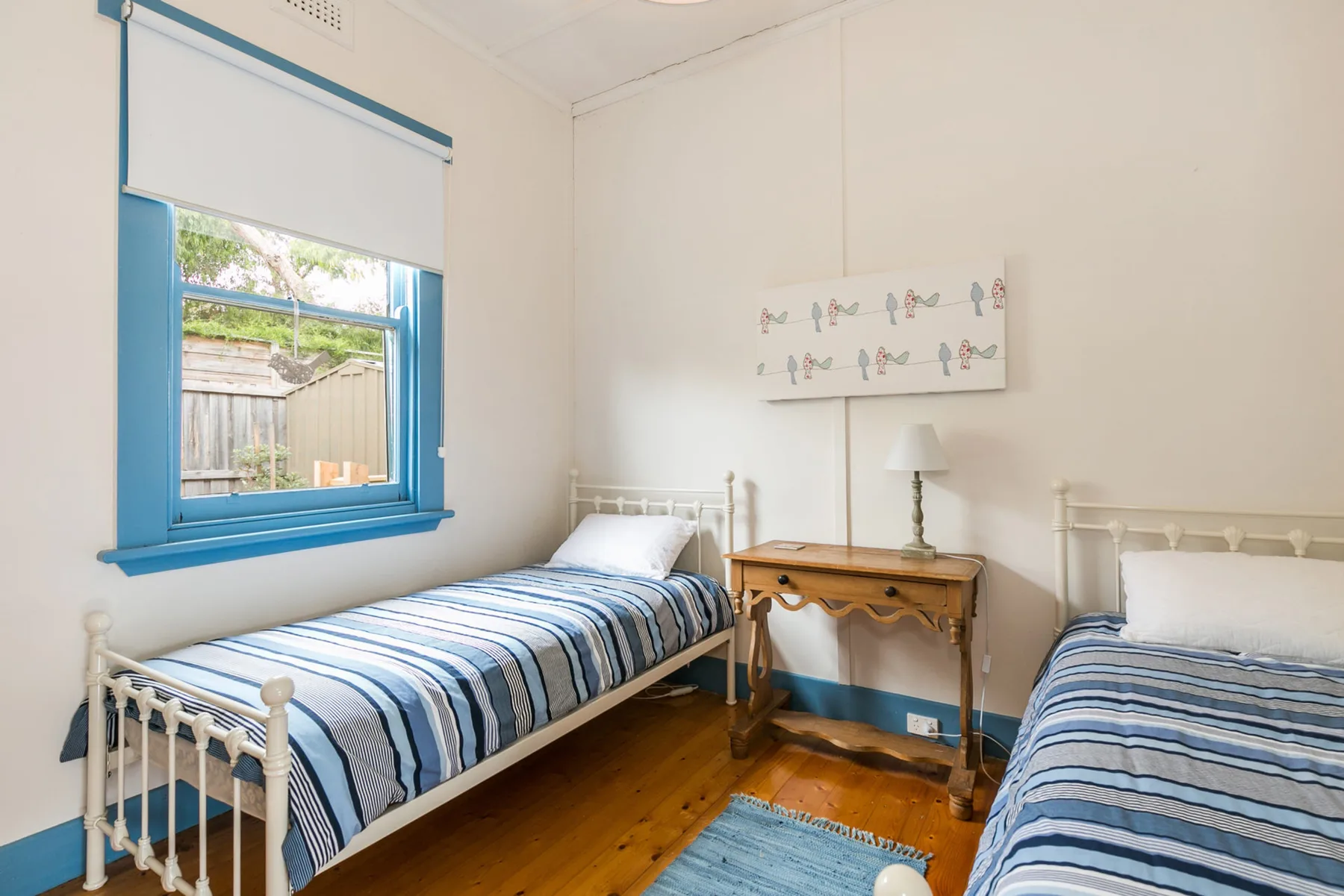 Un dormitorio luminoso con dos camas y una pequeña mesa de madera.