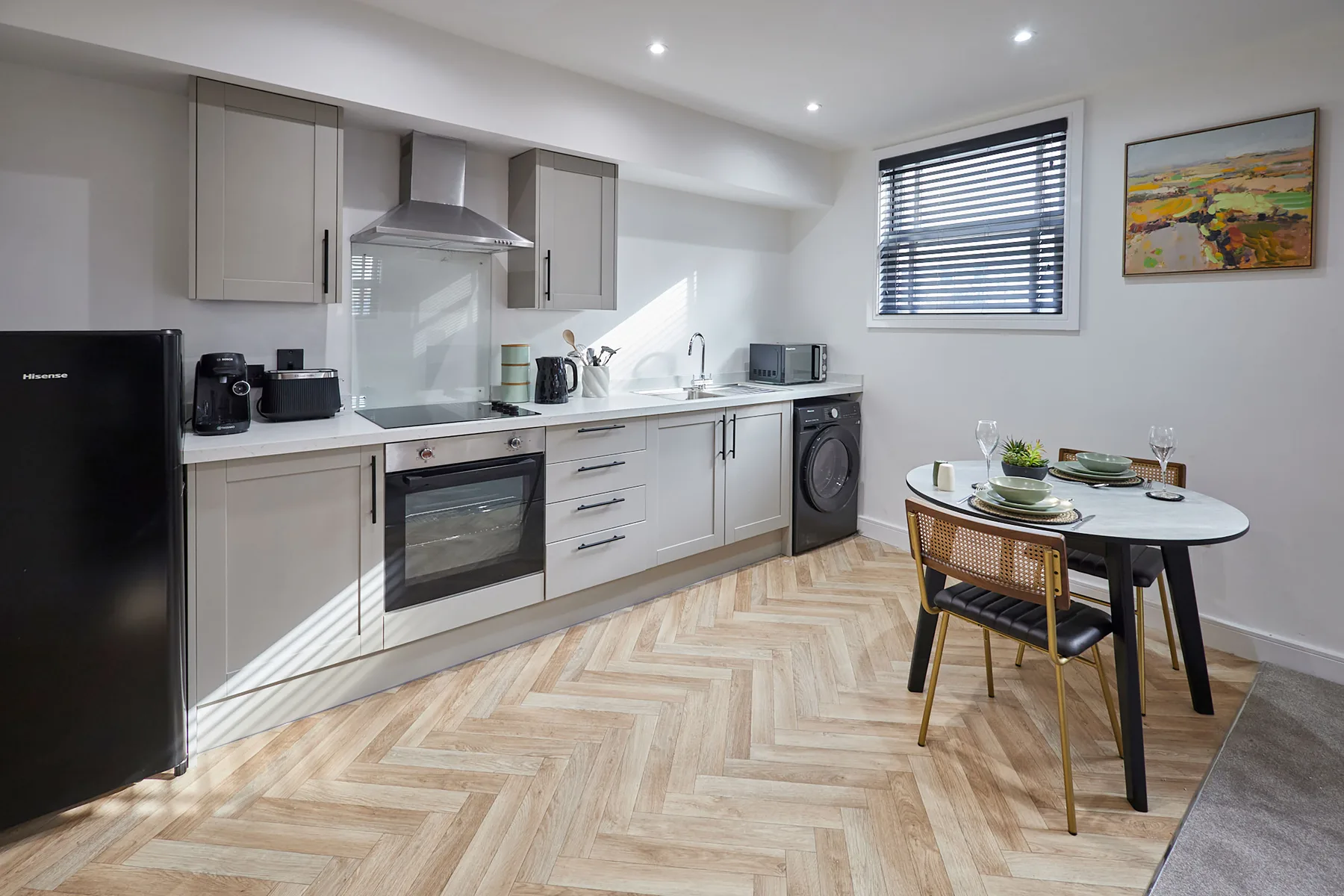 A bright kitchen and dining area with white cabinets, appliances, and a small table.