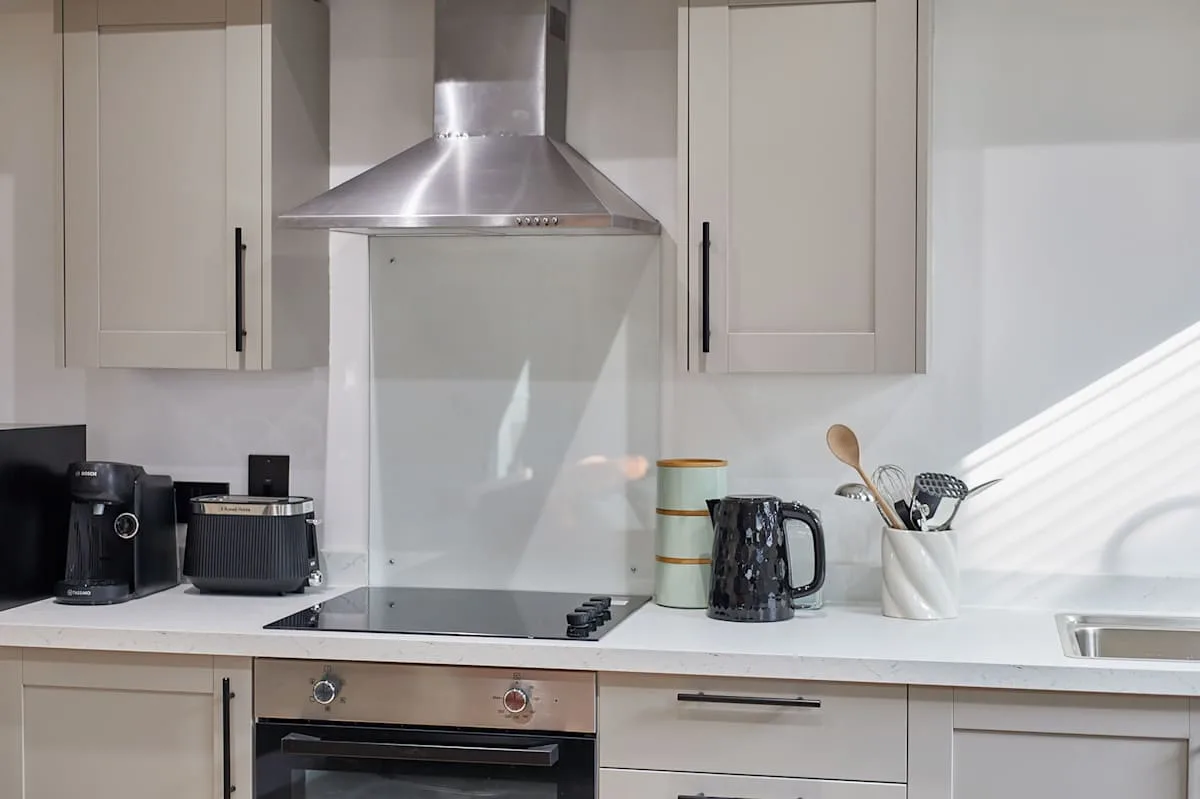 Una cocina luminosa con placa de cocina, horno y pequeños electrodomésticos.