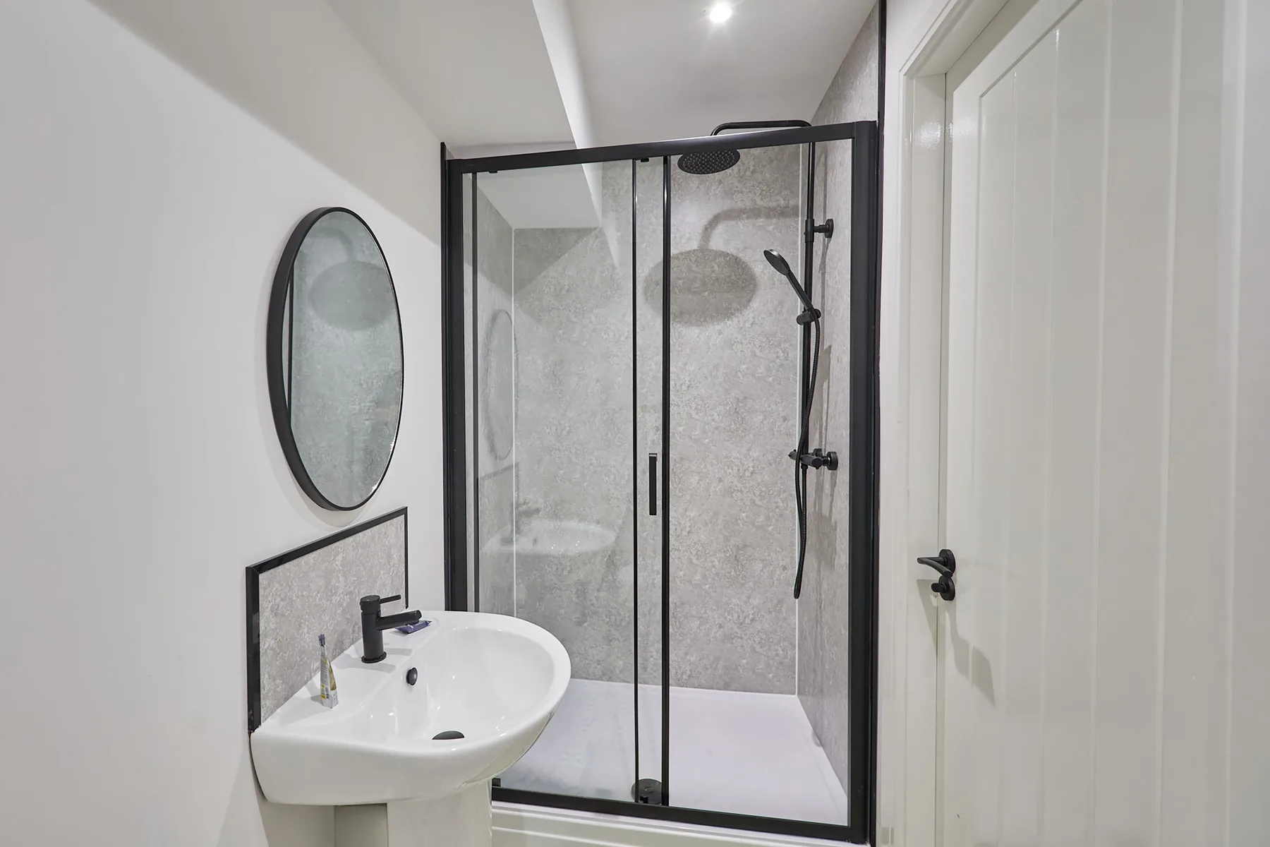 Un baño con lavabo y una ducha con mampara de vidrio.